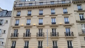 A multi-story hotel with a classic European architectural style, featuring ornate balconies and a central entrance.