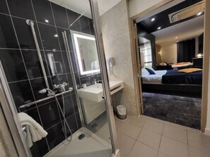 Un baño moderno con cabina de ducha de vidrio, lavamanos blanco y espejo.