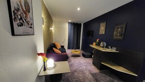 A modern living room with a sofa, a small round table, a coffee table, and a bar area with a counter and shelves.