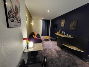 Una sala de estar moderna con un sofá, una mesita redonda pequeña, una mesa de centro y una zona de bar con mostrador y estanterías.