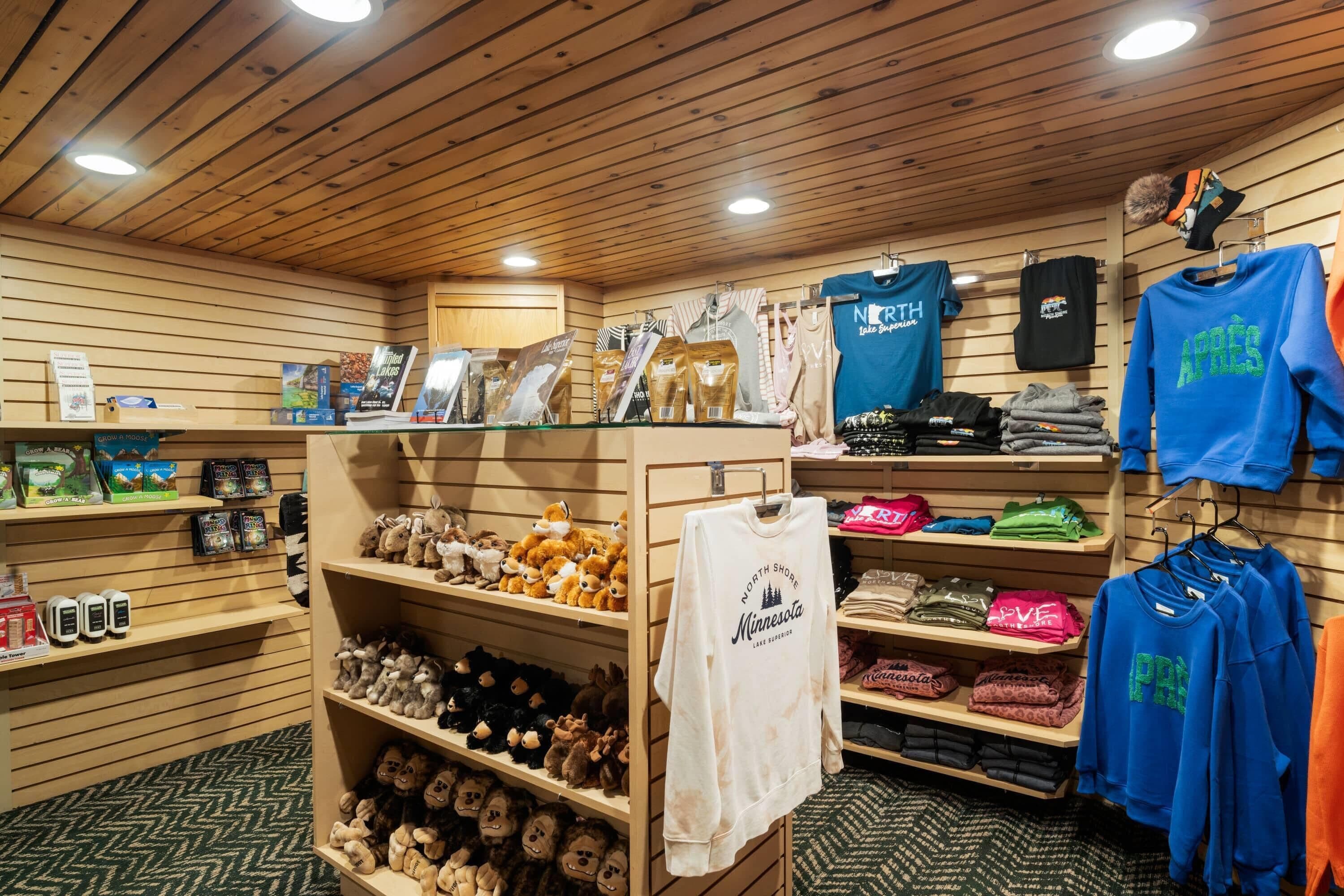 Un magasin de détail avec des étagères en bois où sont exposés divers articles, notamment des peluches, des vêtements et des accessoires.