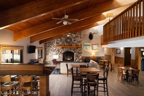 Un interior espacioso con chimenea de piedra, vigas de madera en el techo y una zona de bar.