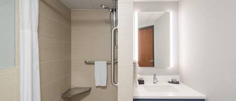 A bathroom with a shower, a sink, and a mirror.