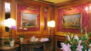 A room with two framed paintings, a table with a teapot, and a vase with flowers. - Hotel Santa Marina (Venice)