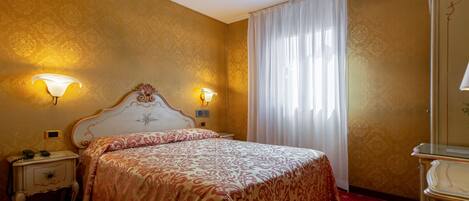 A hotel room with a large bed, two bedside lamps, a nightstand, and a mirror.