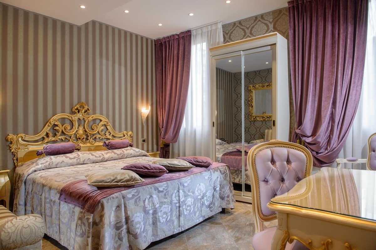 Un dormitorio con una cama grande, un armario de puertas de cristal y una mesa de comedor.