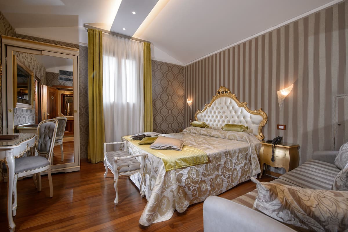 Un dormitorio amplio con una cama grande, una zona de estar y un tocador con espejo.