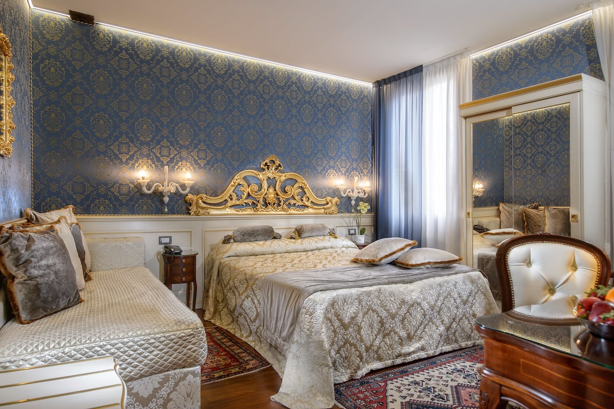 Un dormitorio lujoso con una cama grande, una cama más pequeña y una silla.