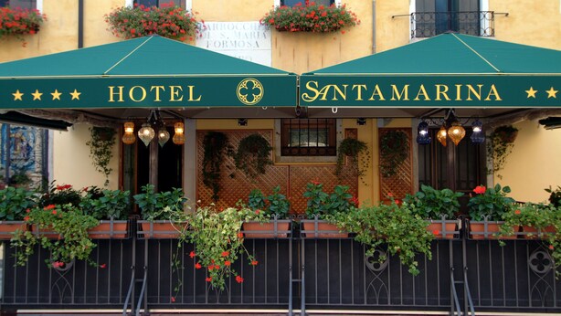 A hotel named Santamarina with a green awning, outdoor seating area, and potted plants. - Hotel Santa Marina (Venice)