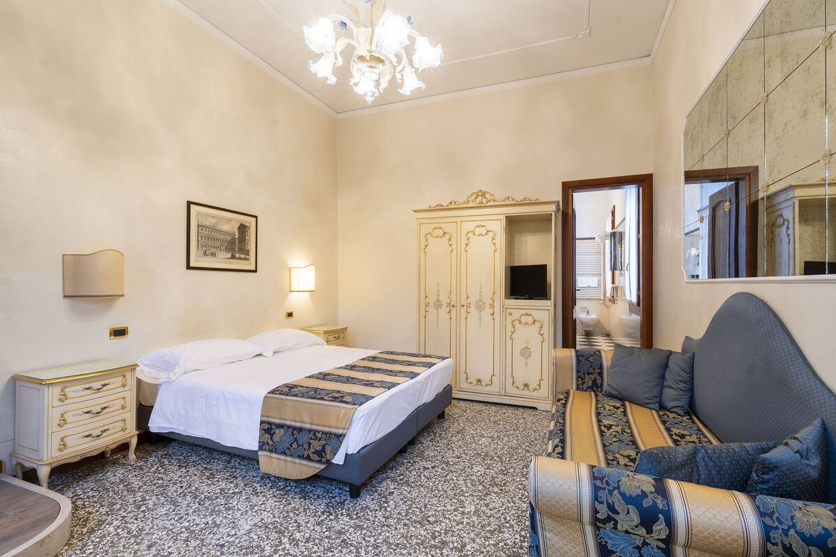 Un dormitorio con cama, cómoda, sofá y candelabro.