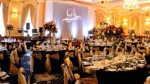 A banquet hall with round tables, chandeliers, and floral centerpieces. - Golden Lion Hotel (Stirling)
