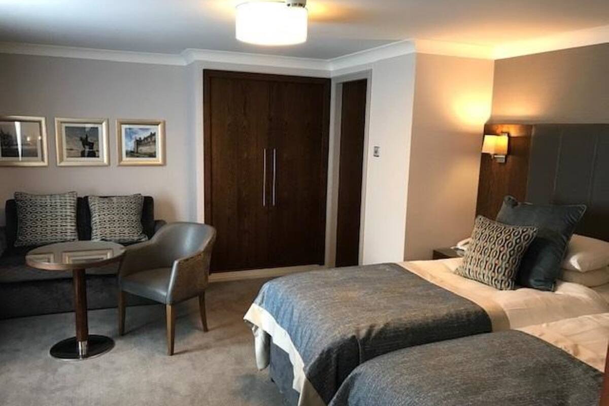 A hotel room with a bed, a desk, a chair, and a wardrobe.