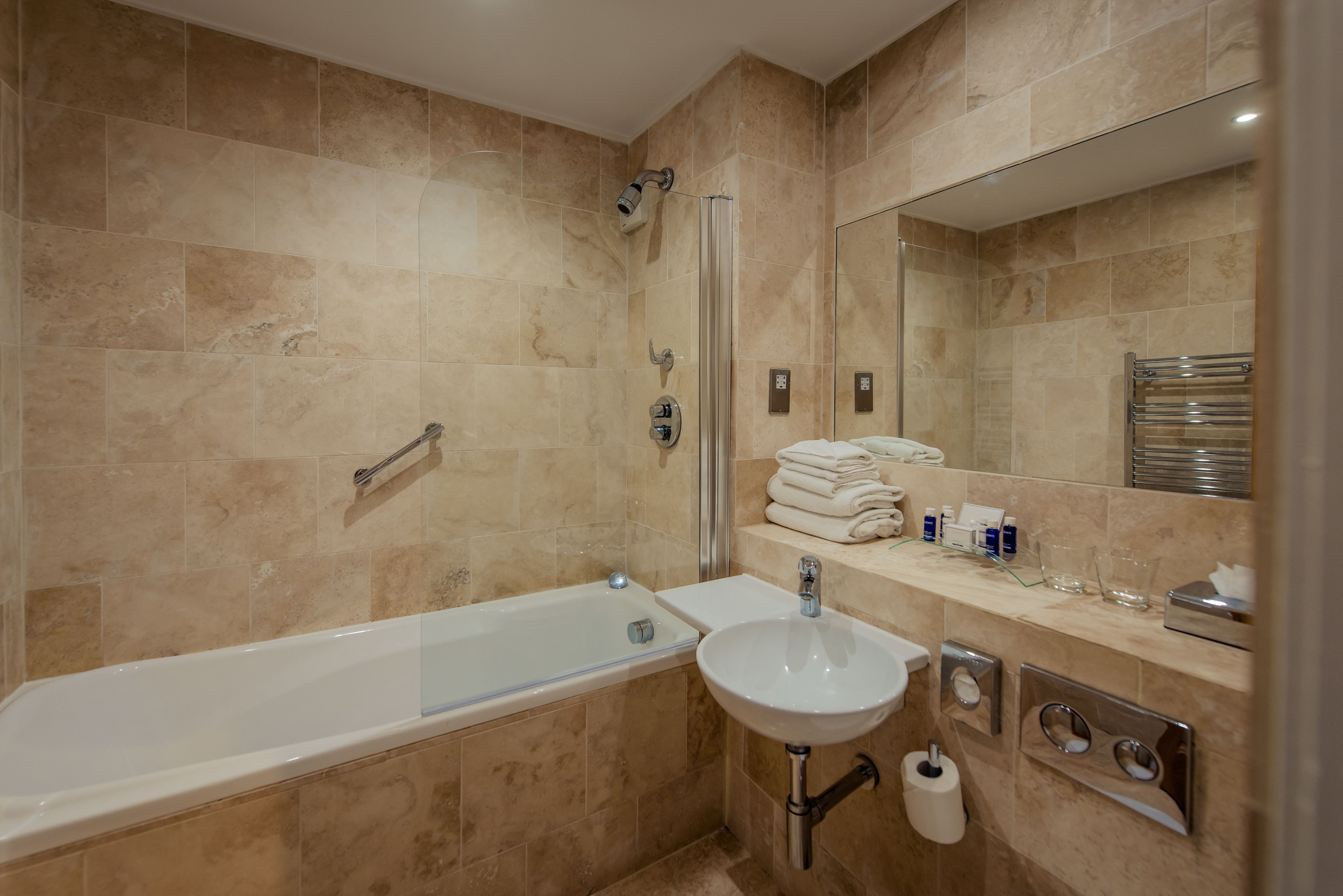 A modern bathroom with a bathtub, sink, and a glass shower enclosure.