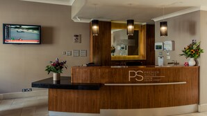 A reception desk with a wooden finish, a flat-screen TV mounted on the wall, and a reception area with a modern design. - Premier Suites Dublin Leeson Street (Dublin)