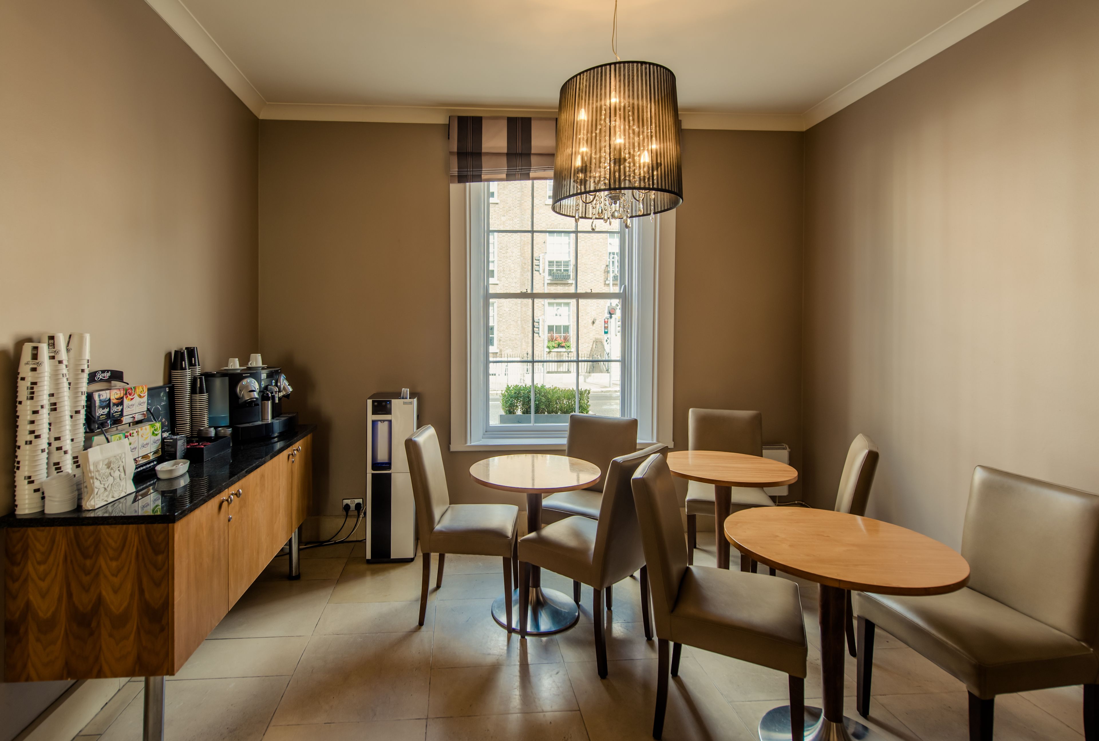 A modern cafe with a wooden counter, round tables, and comfortable seating.