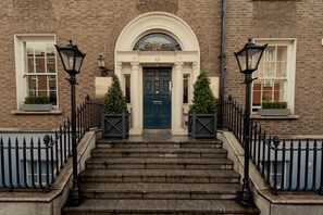 A brick building with a dark blue door, white-framed windows, and a stone staircase leading to the entrance. - Premier Suites Dublin Leeson Street (Dublin)
