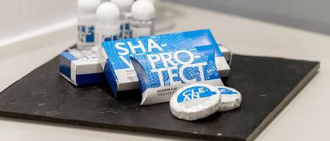 A bathroom counter with a blue and white shower cap kit, a bottle of liquid soap, and a bar of soap.