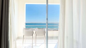 A balcony with two wicker chairs and a glass door leading to a beach view. - TRYP by Wyndham Lisboa Caparica Mar (Almada)