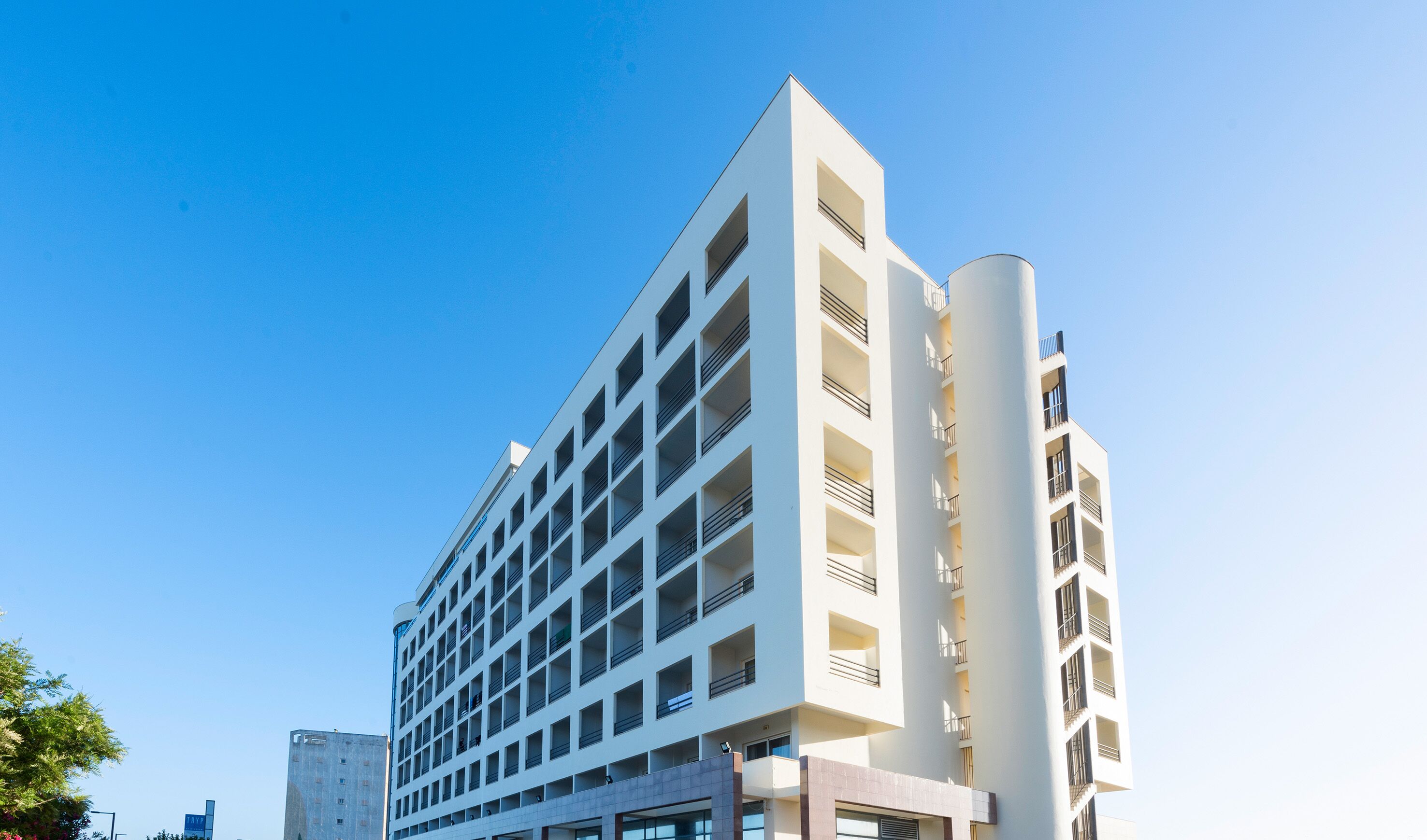 Um hotel com vários andares e design arquitetônico moderno, com um átrio central e varandas em cada pavimento.