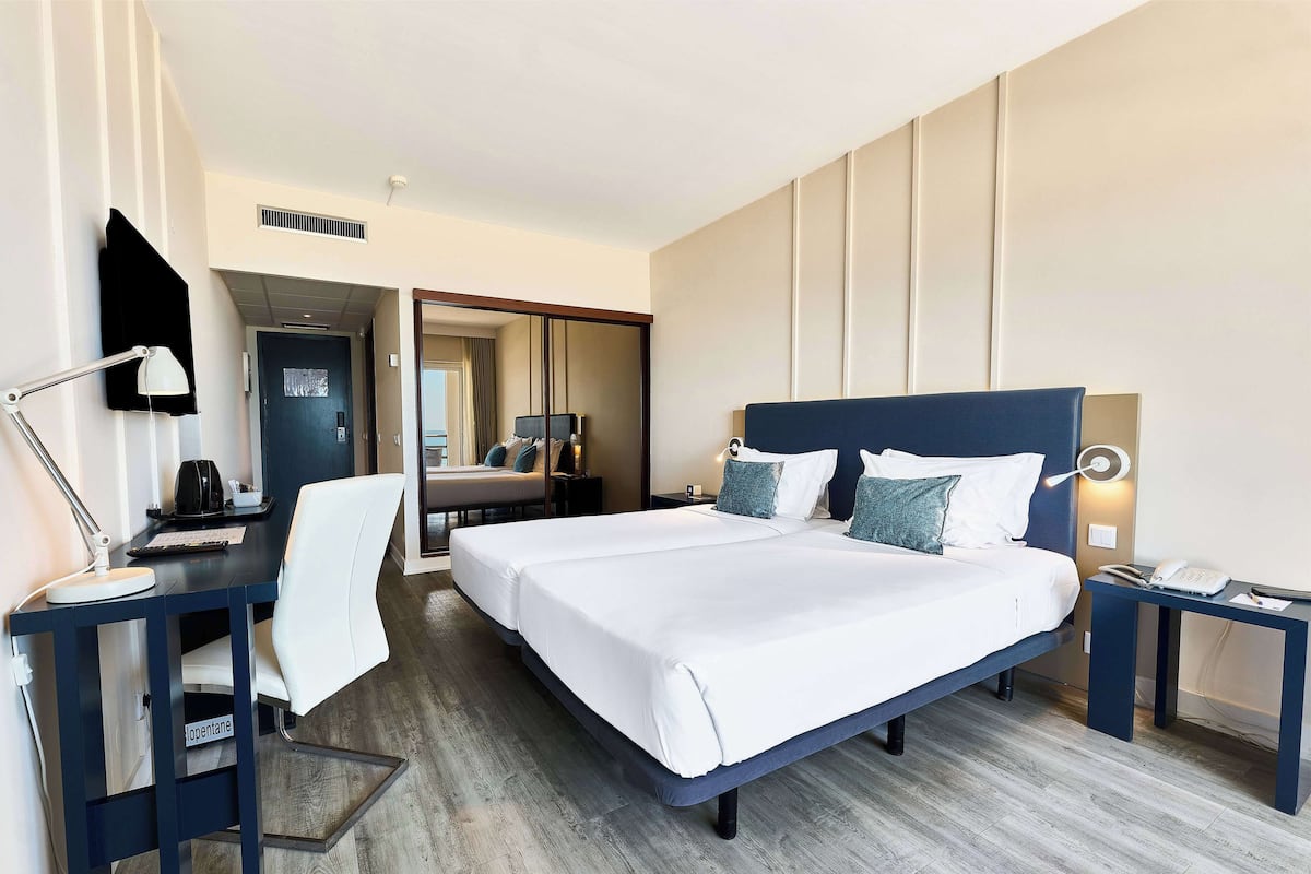 Habitación de hotel con una cama grande, un escritorio con silla, una lámpara de escritorio y un teléfono.