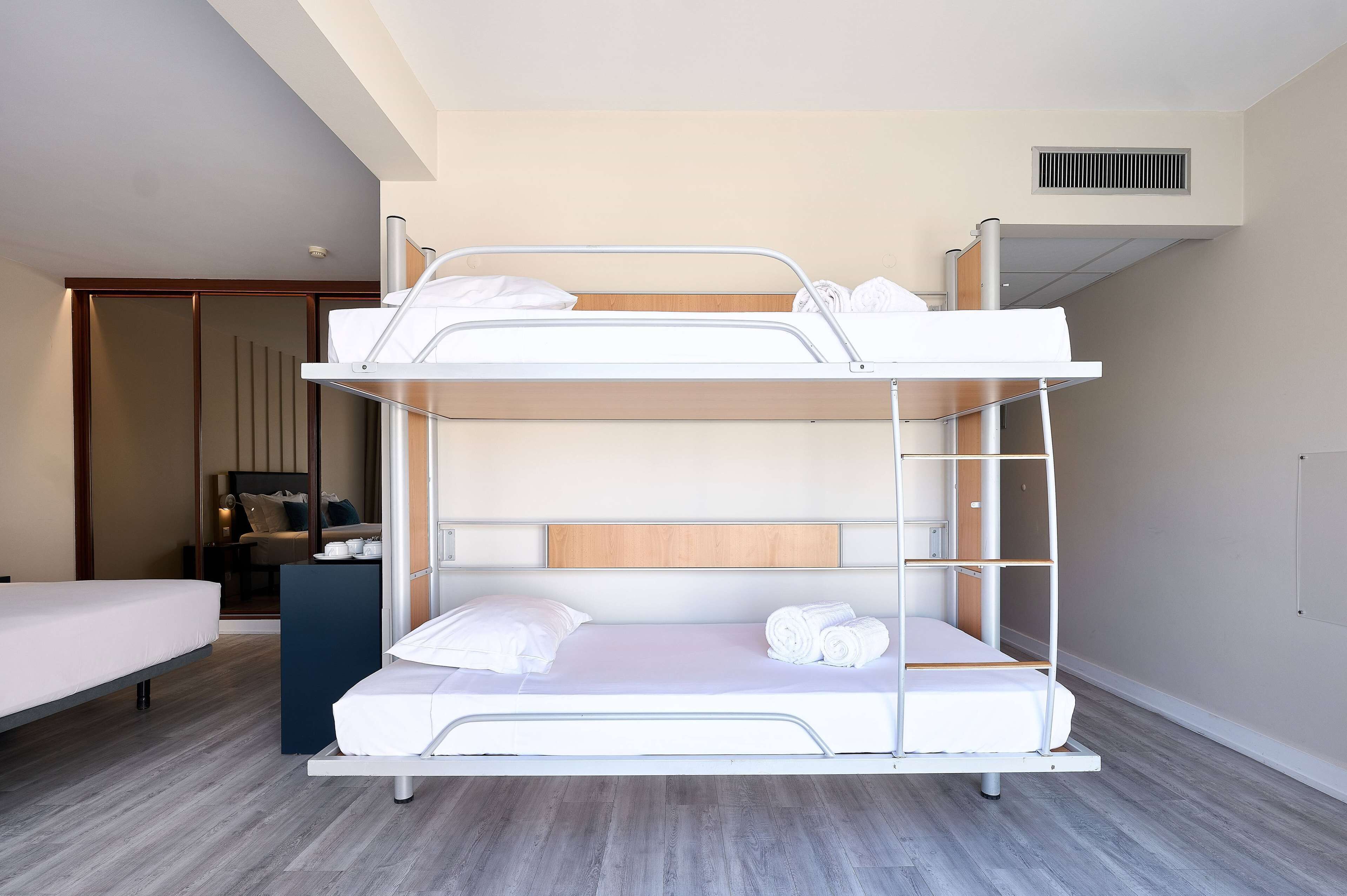 Ein Stockbett mit einem Holz-Kopfteil, einem Nachttisch und einem Spiegel.