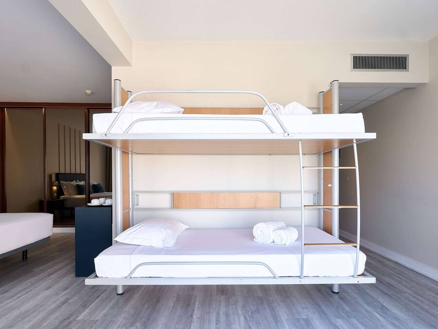 Una cama litera con cabecera de madera, una mesita de noche y un espejo.