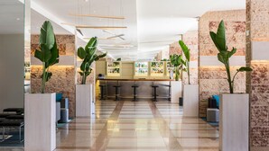 A modern lobby with a checkered floor, seating areas, and a bar with shelves of bottles. - TRYP by Wyndham Lisboa Caparica Mar (Almada)