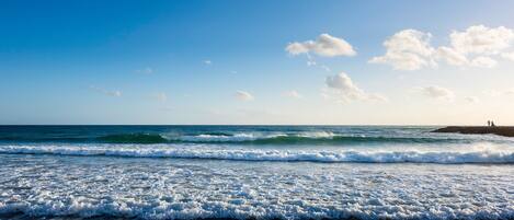 A beach with waves and a clear sky.