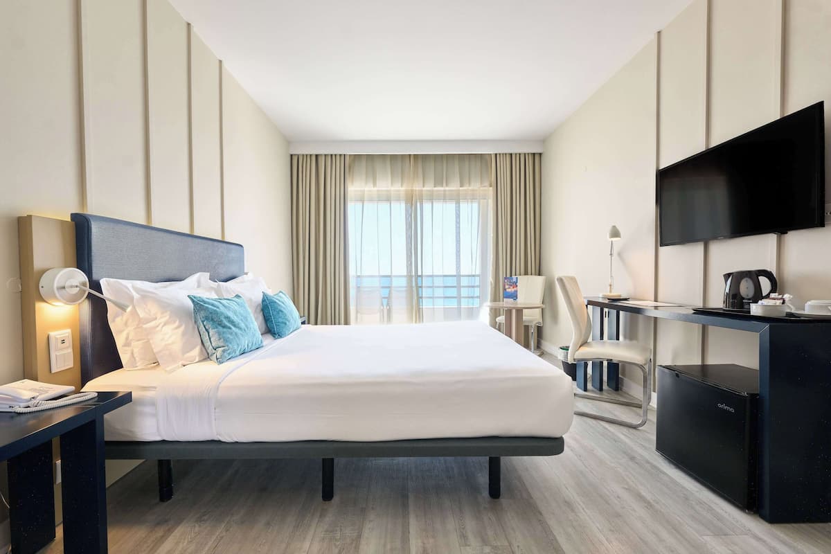 Habitación de hotel con cama, escritorio y televisor.
