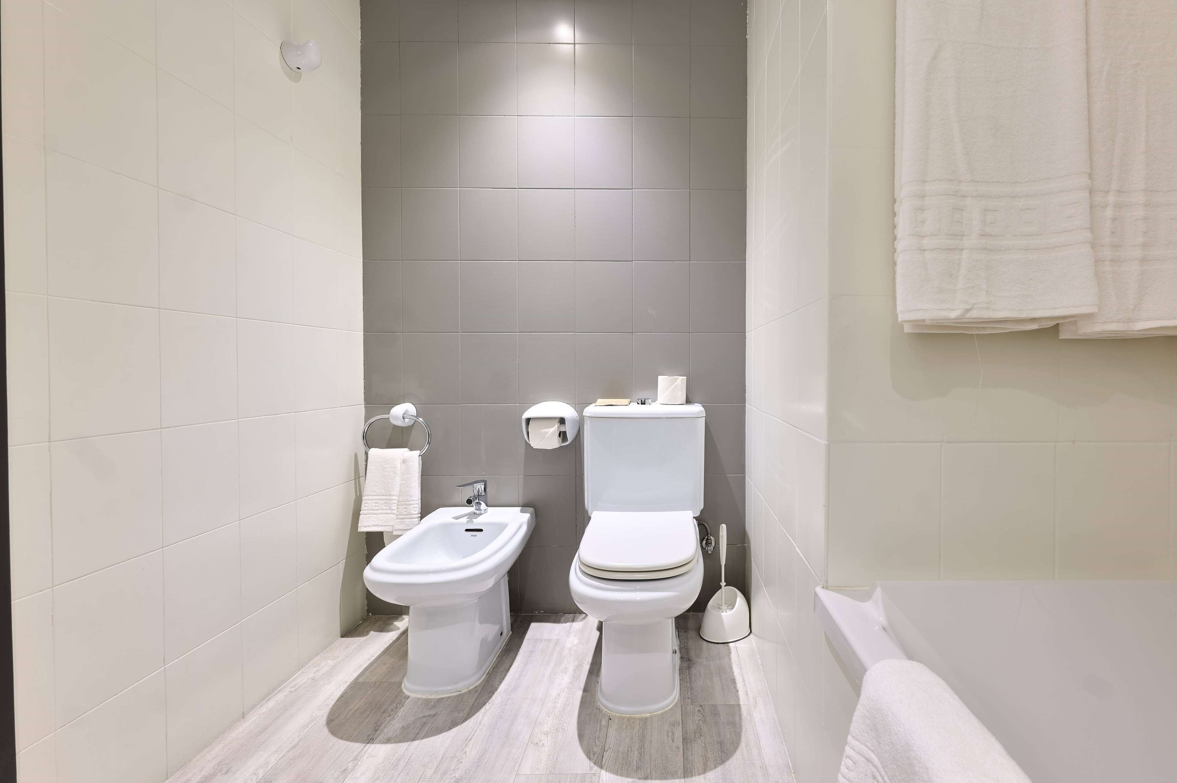 A modern bathroom with a bidet, toilet, and bathtub.