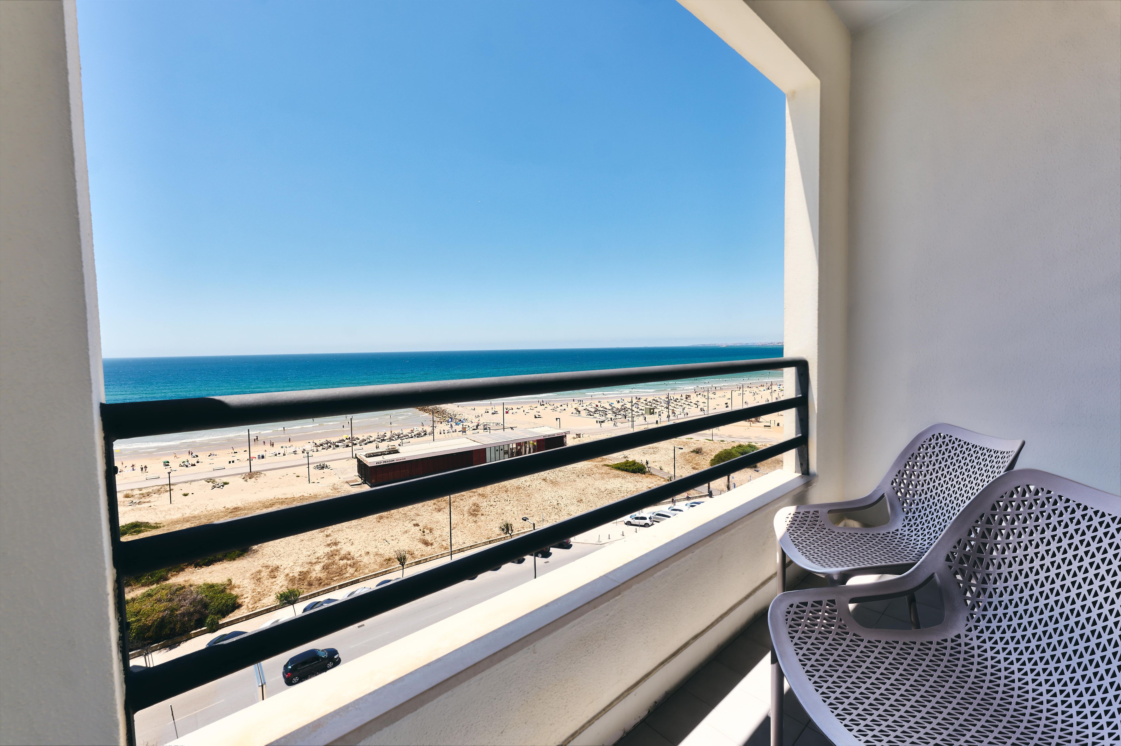 Un balcón con vista a la playa y un estacionamiento.