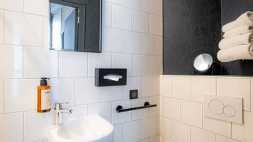A modern bathroom with a white sink, a mirror, a towel rack, and a soap dispenser.