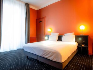 A hotel room with a large bed, two bedside tables with lamps, a door, and a window with curtains.