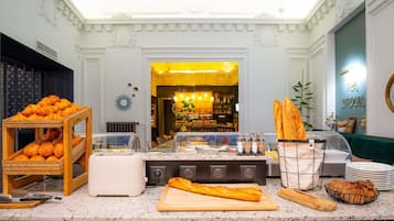 A breakfast buffet area with various pastries, bread, and a coffee station.