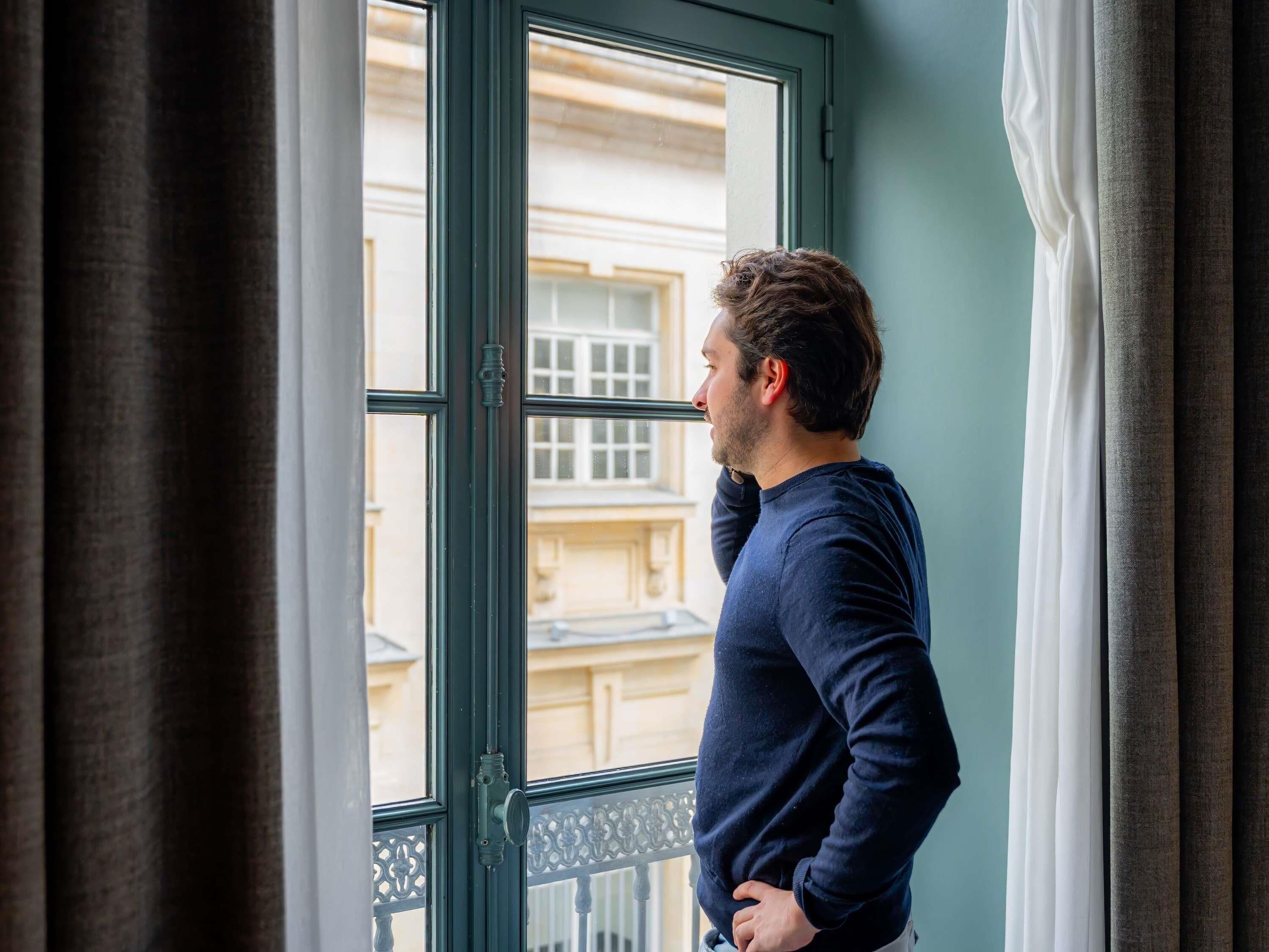A person standing by a window with a view of buildings outside.