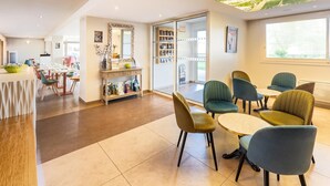 A modern hotel lobby with a dining area, a children's play area, and a large window with a view. - Sure Hotel by Best Western Rennes Chantepie (Chantepie)