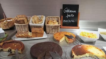 En buffet med forskellige bagværk og desserter, heriblandt kager og brød.