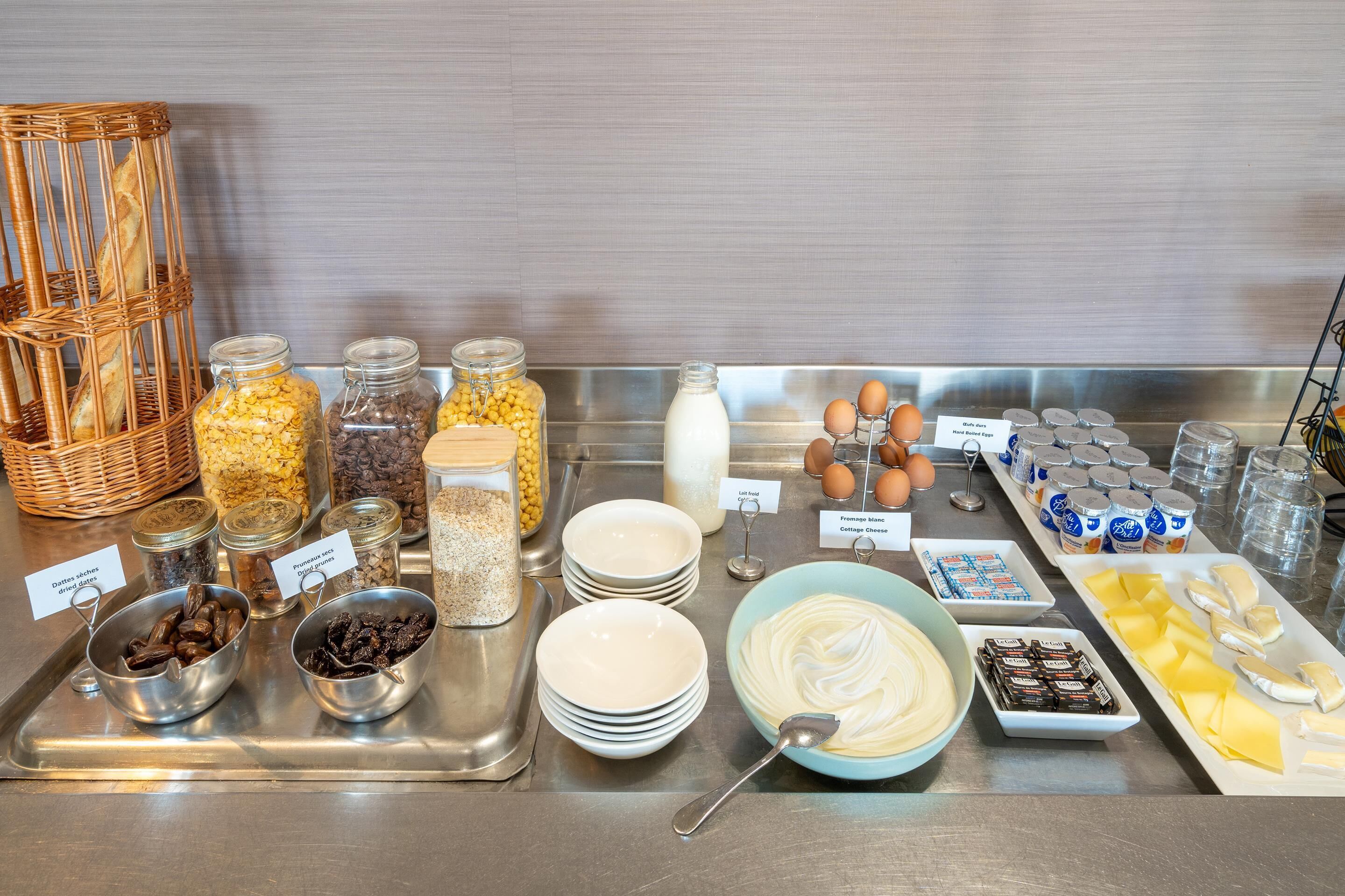 A buffet with various food items including bread, fruits, eggs, and dairy products.