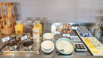 A buffet with various food items including bread, fruits, eggs, and dairy products.