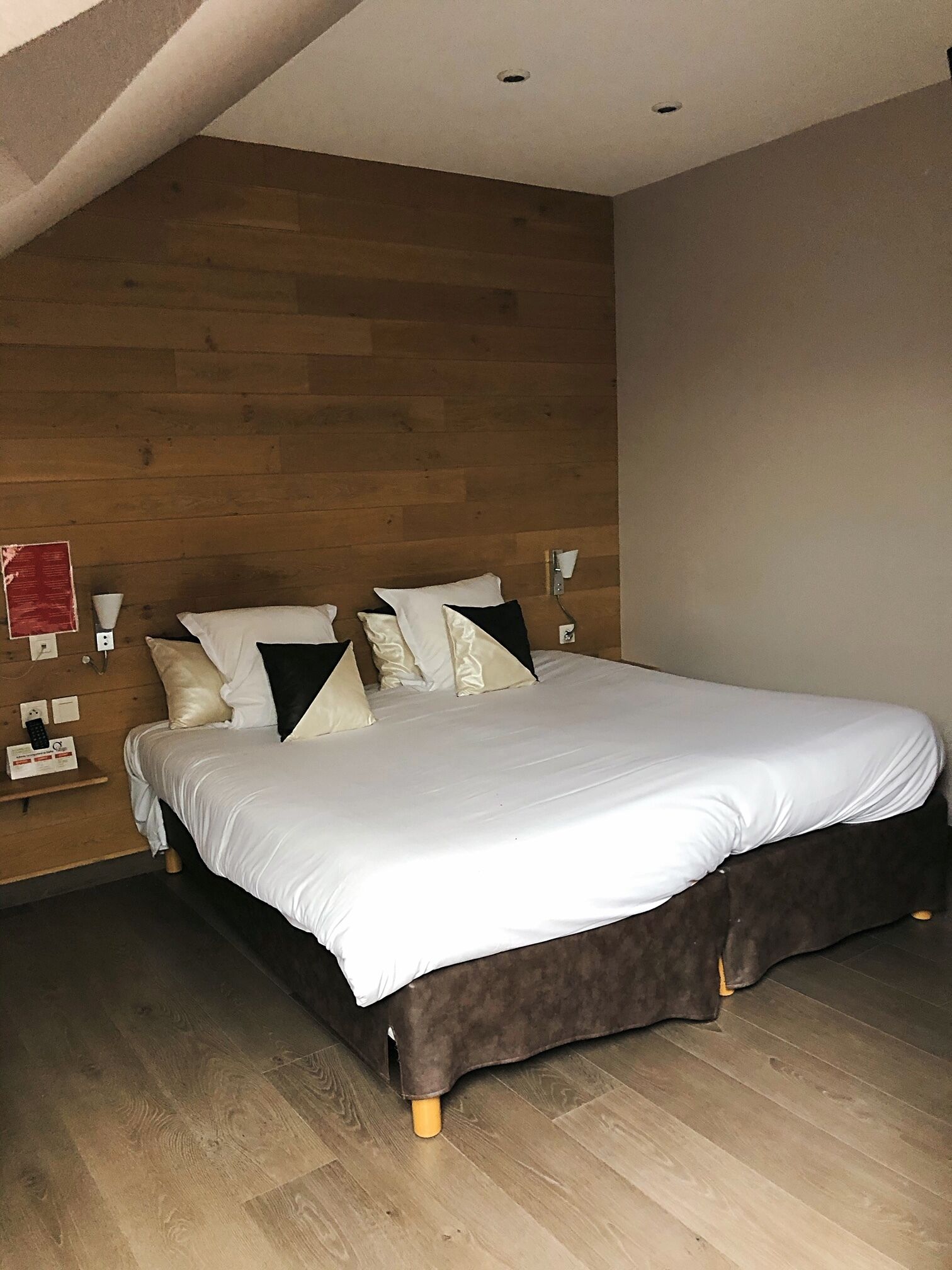 Un dormitorio con una cama grande, cabecera de madera y una mesita de noche con lámpara.