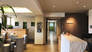 A modern hotel lobby with a reception desk, seating area, and a green wall with a projection. - Sure Hotel by Best Western Rennes Chantepie (Chantepie)