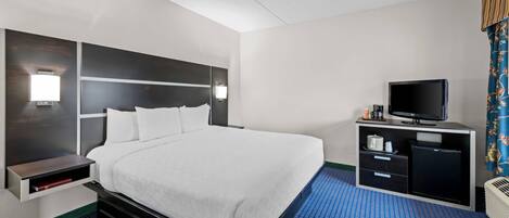 A hotel room with a large bed, a TV, a minibar, and a desk.