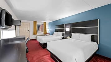 Ein Hotelzimmer mit zwei Betten, einem Schreibtisch und einem Fernseher, sowie einem roten Teppich.