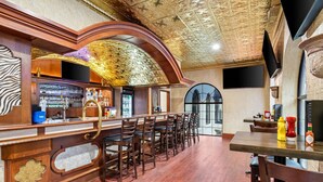 Zona de bar con mostrador de madera, taburetes y techo decorativo.