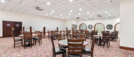 A conference room with multiple tables and chairs, a patterned carpet, and ceiling lights.