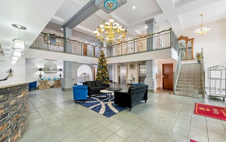 A spacious lobby with a Christmas tree, seating area, and a staircase leading to an upper floor.
