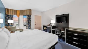 Una camera d'albergo con un letto, una scrivania, una sedia, televisore e una porta.