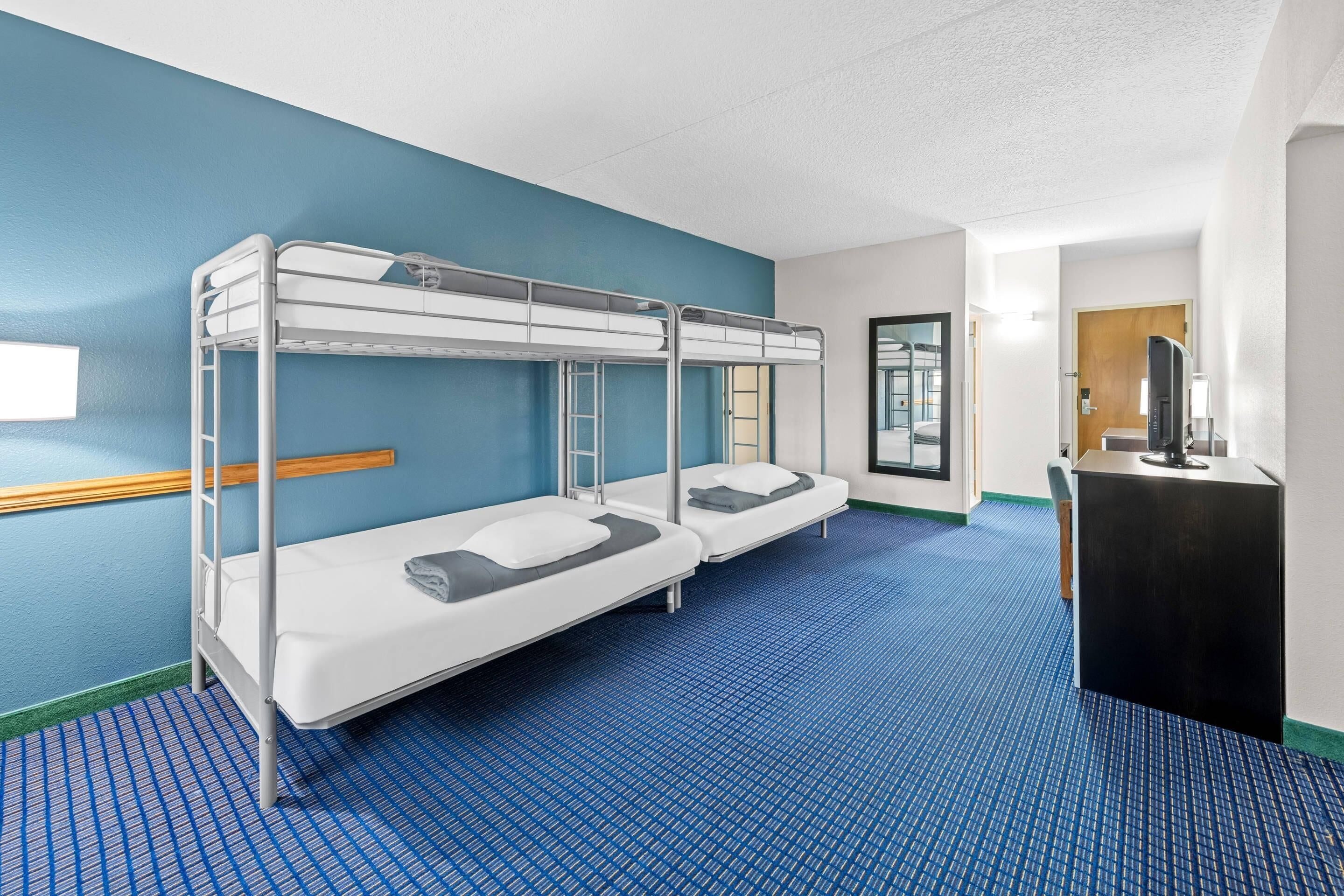 A bunk room with two beds, a desk, and a television.
