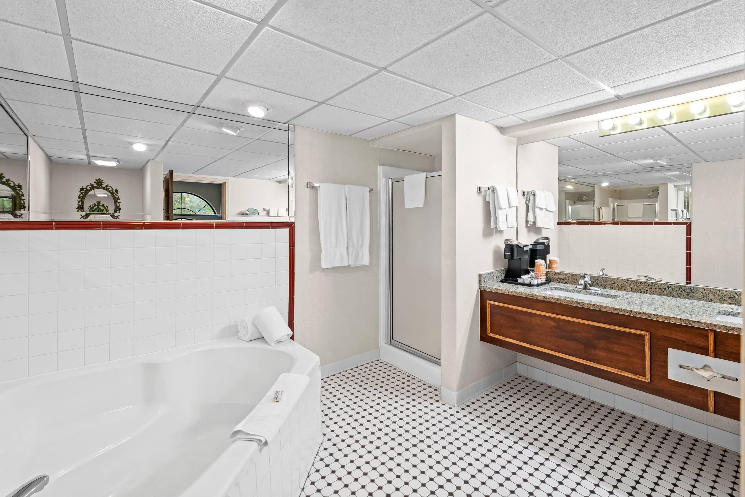 A modern bathroom with a bathtub, a shower, a vanity with a mirror, and a tiled floor.