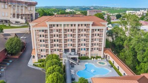 Un hotel de varios pisos con piscina, estacionamiento y vistas del entorno.